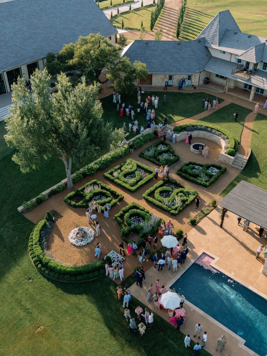 Aerial view of The Bower courtyard: boxwood gardens, a fountain, and the pool, filled with guests
